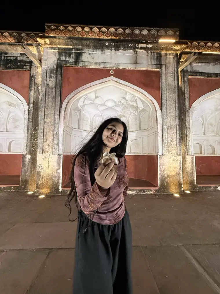 Bhumika in front of lit stone arches at night